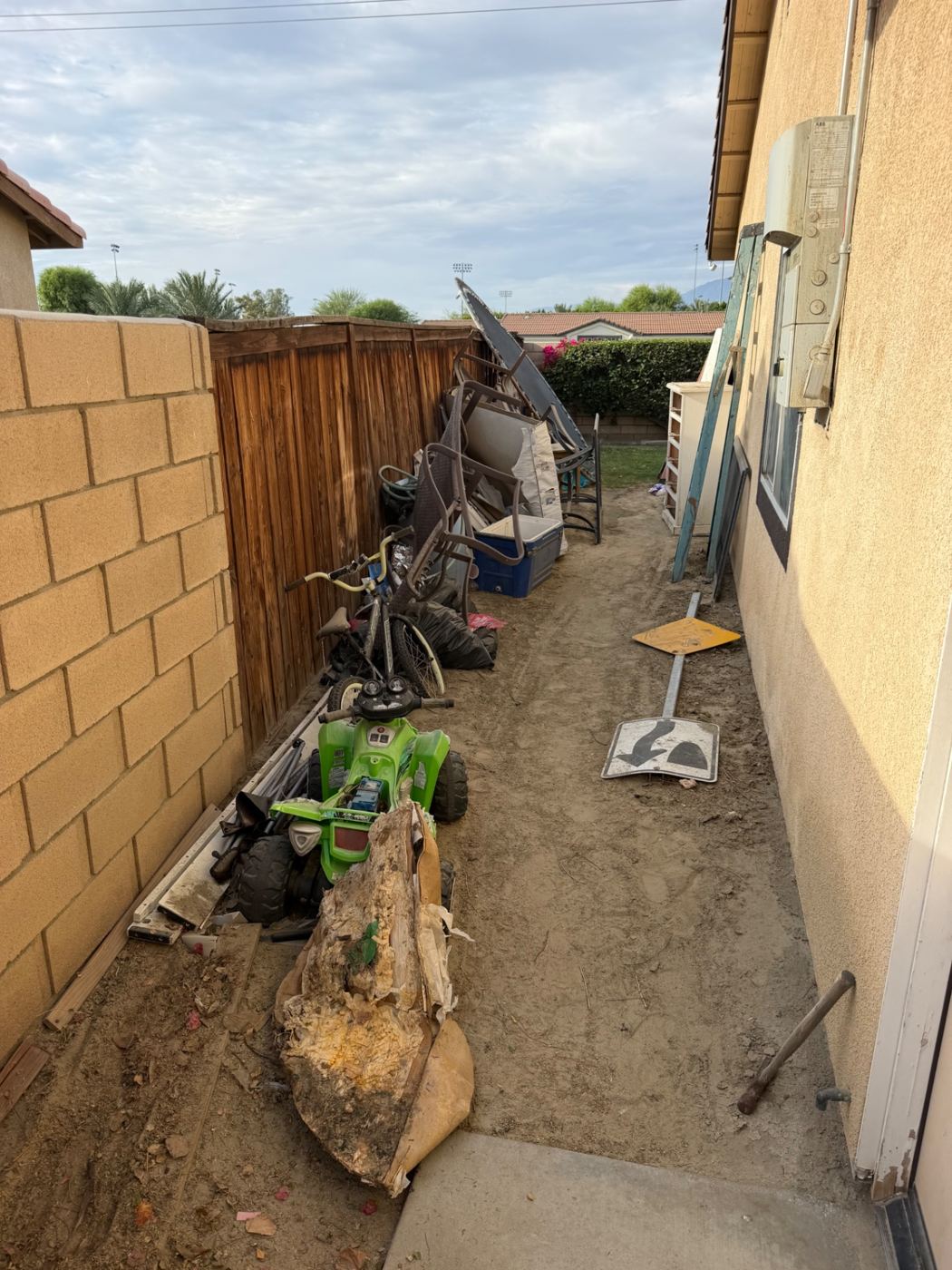 Side yard filled with old patio furniture, toys and debris before junk removal